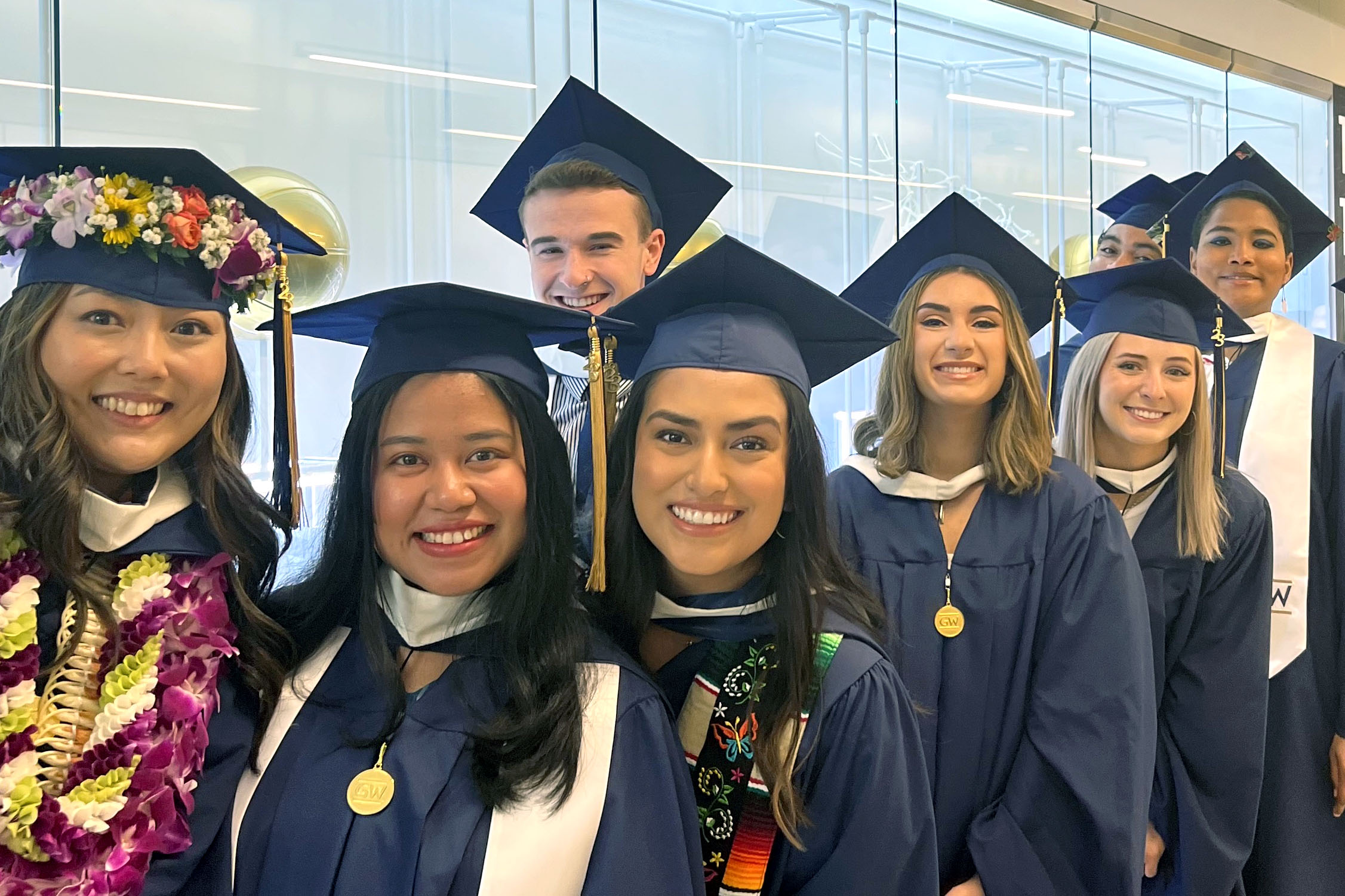 A group of MA in WGSS graduates wearing caps and gowns and smiling
