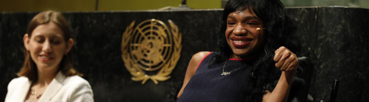 Two people smiling on a stage with a gold seal in the background