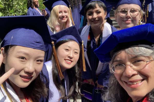 A group of WGSS majors in graduation regalia take a selfie with WGSS faculty